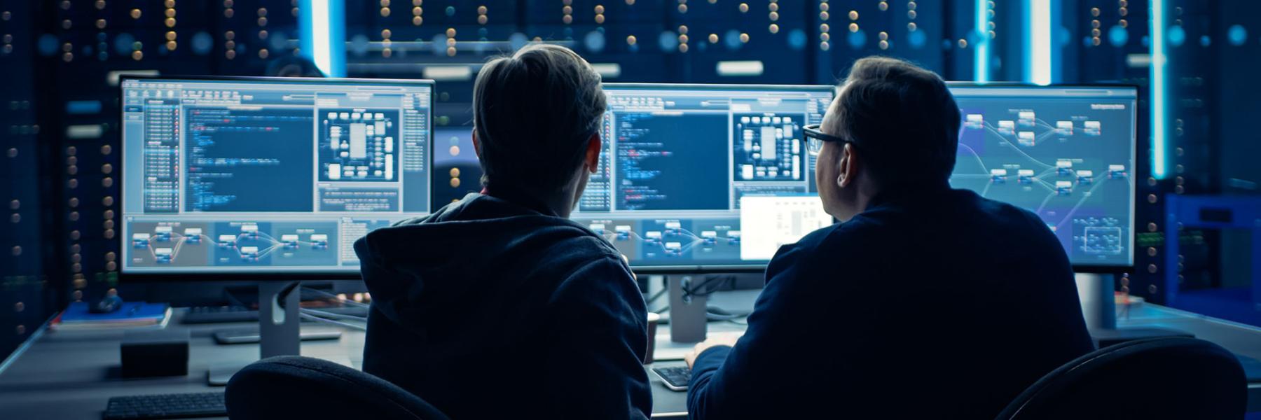 Two employees sitting at computer monitors. 