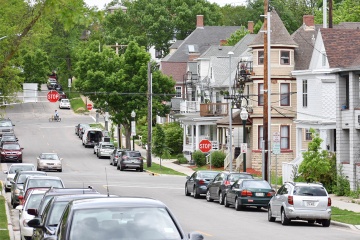 Residential street with many cars parked on the curb.