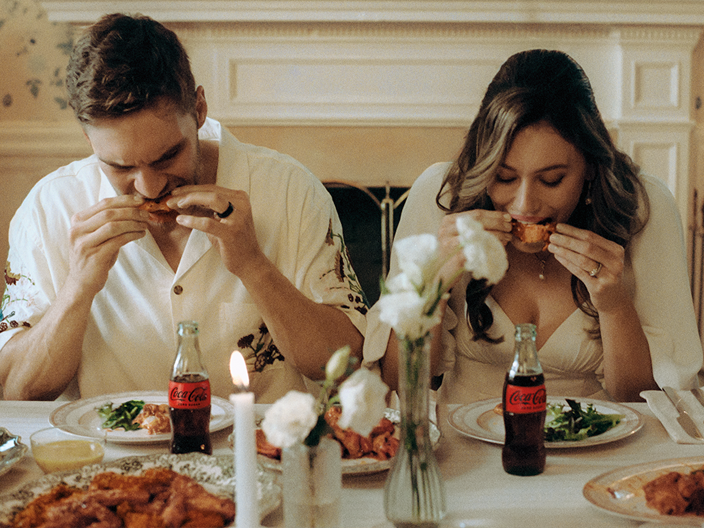 A man and a woman with colorful clothes holding a Coca-Cola bottle