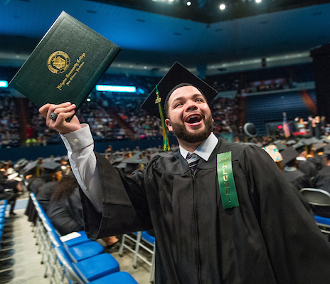 male student graduating and holding up diploma