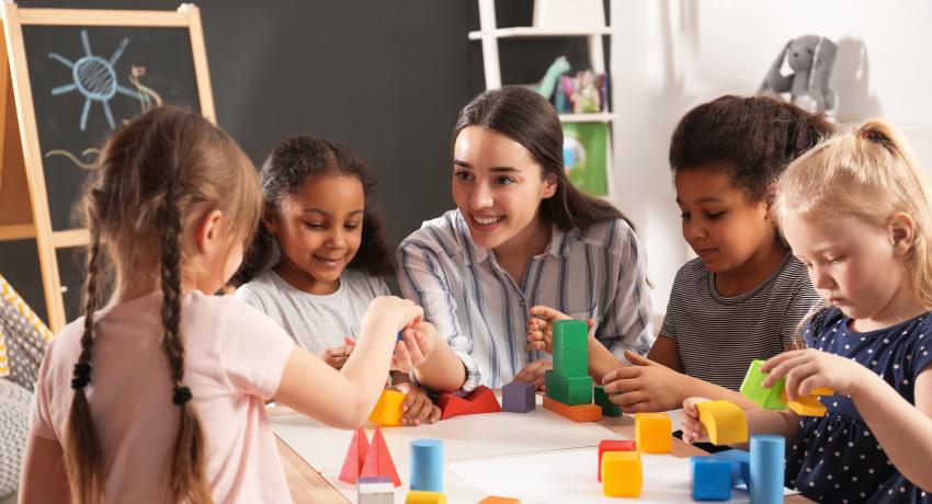 Woman with four children at table playing.