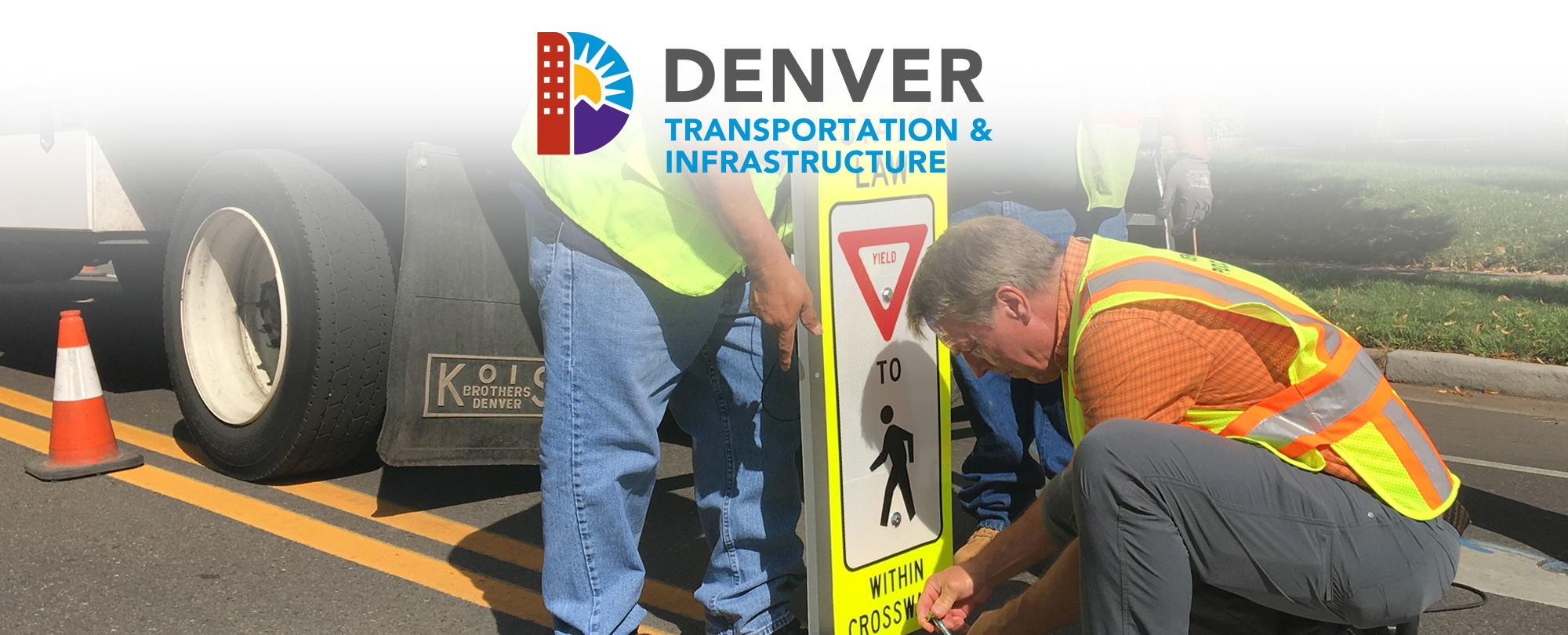 Crews in safety vests installing pedestrian crossing sign