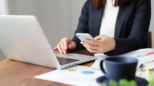 Woman using computer and phone