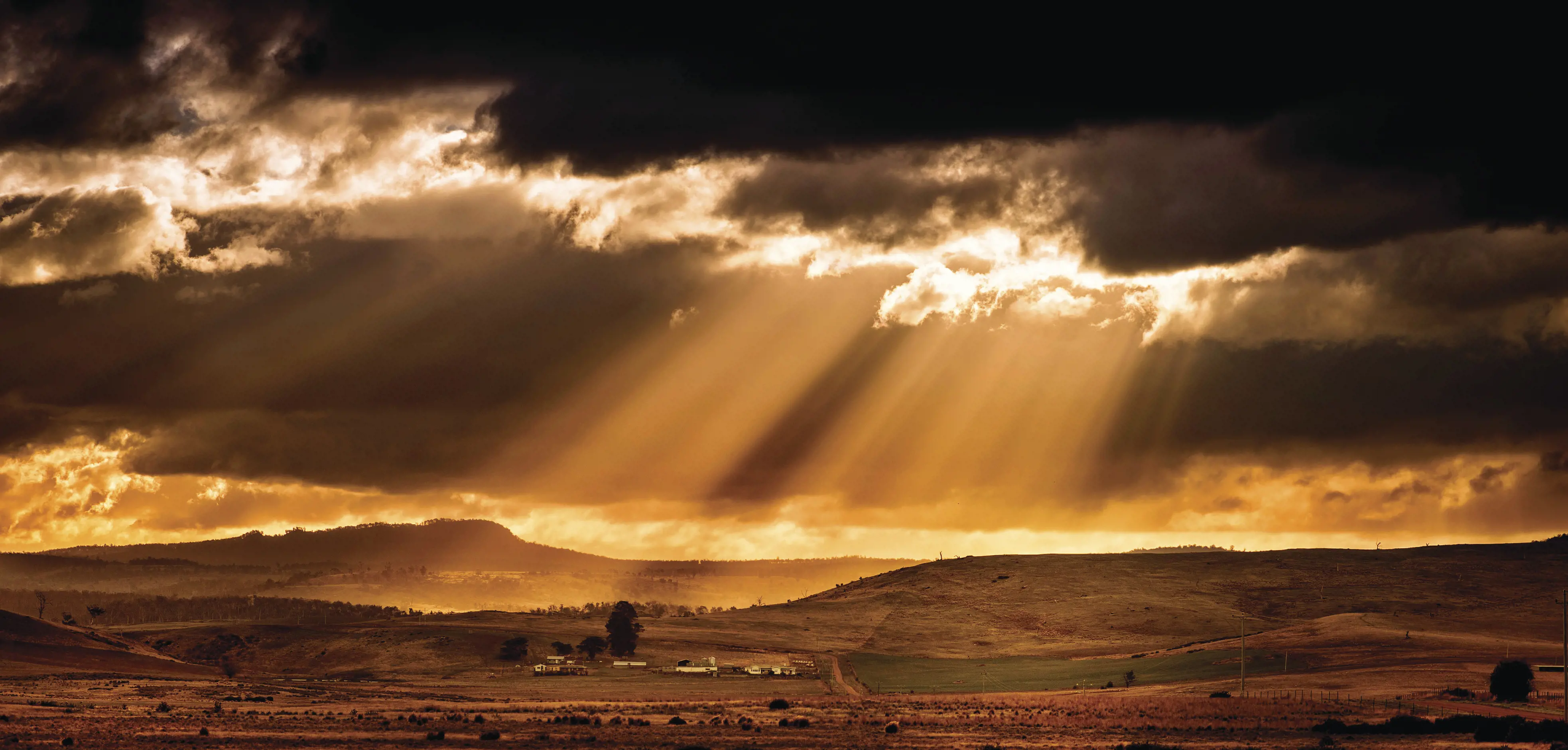 The sun setting over the beautiful farm on the Midlands Highway. The sun shining through the clouds.