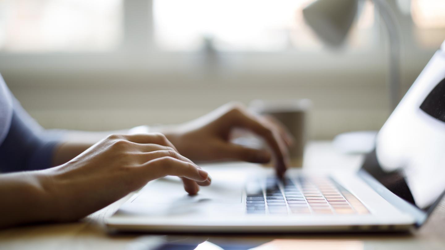 woman's hands using a laptop inside