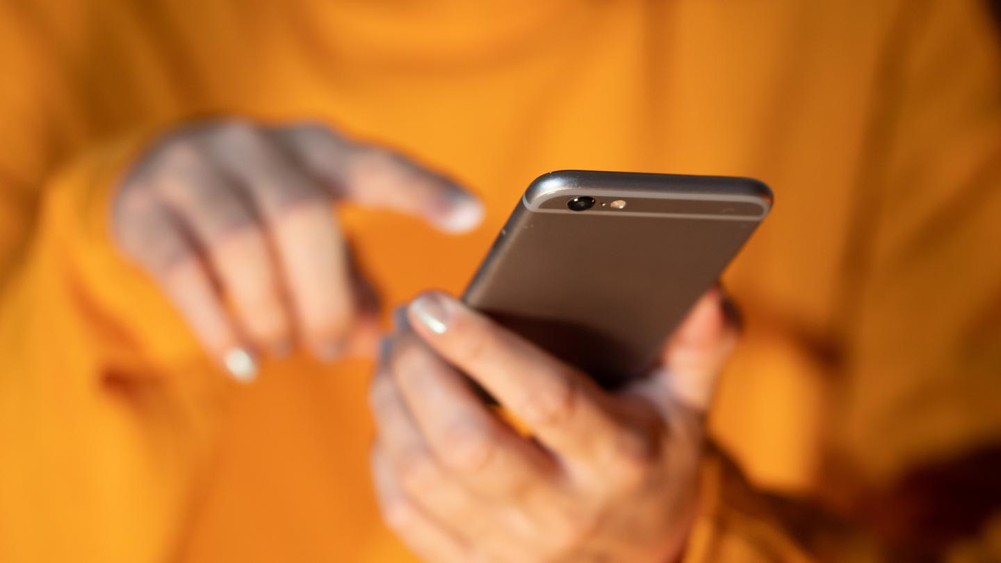 woman in yellow shirt touching cell phone