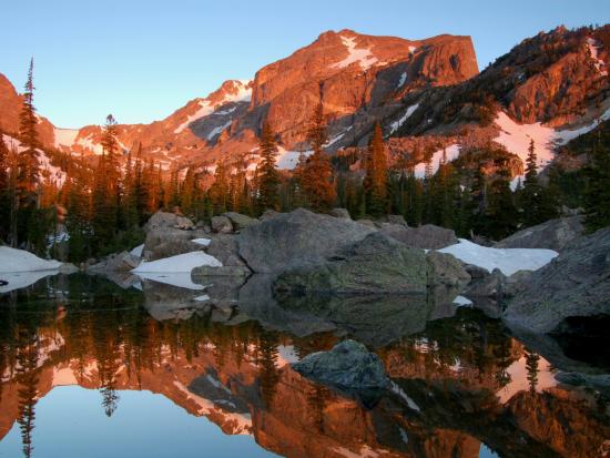 Snow covered mountains and evergreens reflected in a lake