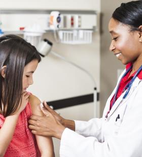 african american doctor gives a child a bandaid after a vaccine