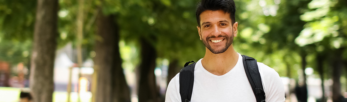 Male student holding a book and smiling