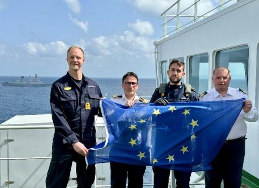 Four naval crew on deck with an EU flag.