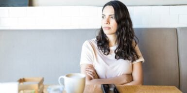 A woman at a café alone looking annoyed and staring into space