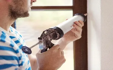 man caulking a window