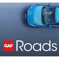 Blue car driving on street with new GAF Roads roadway maintenance