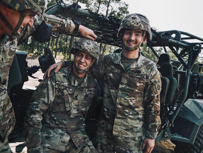 A male Soldier smiles and poses for a photo with his arm around another Soldier