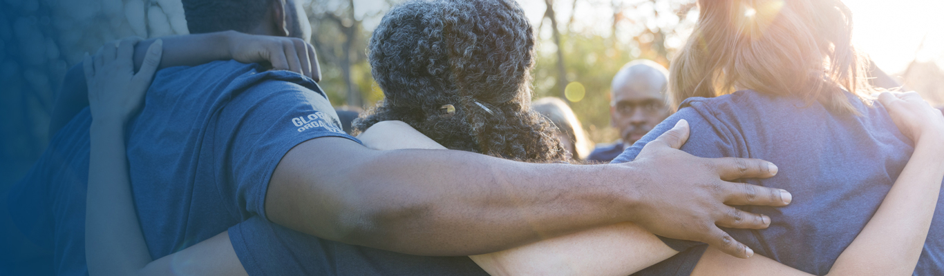 photo of a group of people embracing shoulder to shoulder 