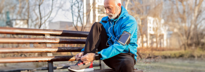 adult senior male tying his shoes on a park bench 