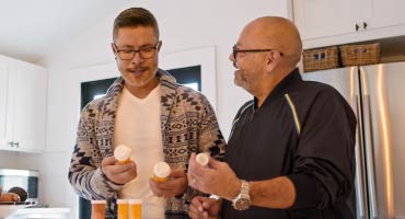 two men looking at their prescription bottles