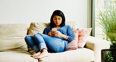 Adult man sitting on a chair in a home looking out a window to illustrate mental health disorders