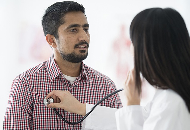 doctor listening to male patient's chest - heart and vascular institute