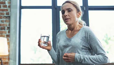 A woman sweating and drinking water