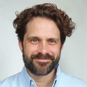 headshot of a smiling man with dark hair