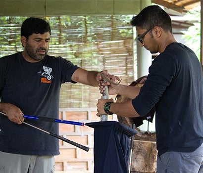 Two men carefully handle a snake contained safely within a bag