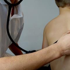 A doctor listens to a child's lungs via a stethoscope