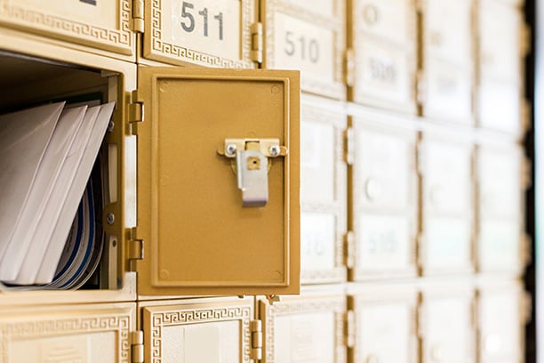 A communal letterbox with one compartment open, with four letters inside