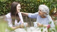 Teenage Granddaughter Relaxing With Grandmother In Garden