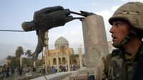 A U.S. SOLDIER WATCHES A STATUE OF PRESIDENT SADDAM HUSSEIN FALL IN CENTRAL BAGHDAD