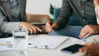 Close-up of couple signing contract with insurance agent in the office.