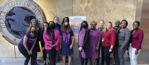 OVW staff take photo in front of Department of Justice Seal