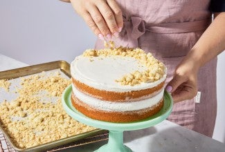 Cake crumbs being sprinkled on top of cake