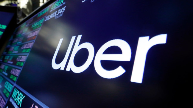 FILE - The logo for Uber appears above a trading post on the floor of the New York Stock Exchange, Aug. 16, 2019. The ride-hailing and delivery company said Wednesday, Oct. 4, 2023, that its drivers will collect up to five prepaid and sealed packages and drop them off at a local post office or at UPS or FedEx stores. Uber will charge a flat fee of $5 for the service or $3 for its Uber One members. (AP Photo/Richard Drew, File)