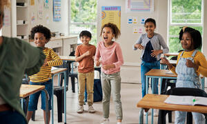 Five children standing and participating in a classroom activity.