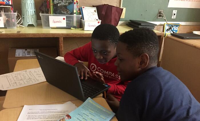 Two young students sitting in front of a computer together.