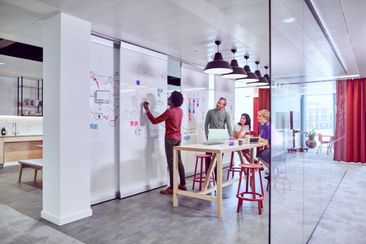 A team of four brainstorming on a whiteboard wall