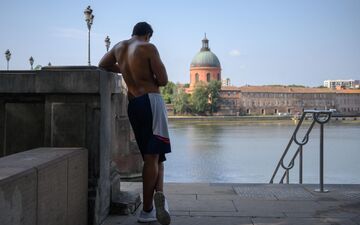 Toulouse (Haute-Garonne), le 28 juillet. Un homme attend torse nu aux abords de la Garonne. AFP/Ed Jones