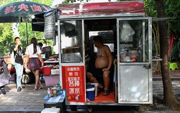 Wuhan (Chine), jeudi. Un vendeur sert les clients torse nu en raison de la chaleur. AFP/Pedro Pardo