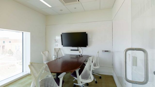 A typical study room at the Hunt Library, with a table, a screen, five chairs, and walls with whiteboard surfaces