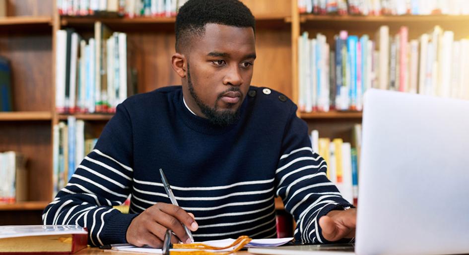 Law student at table in library using a laptop