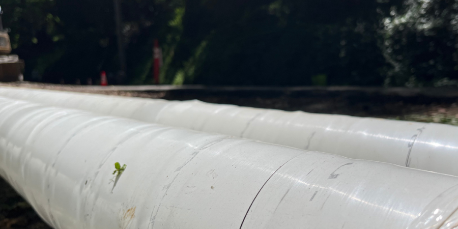 Two pipes sit alongside a roadway.