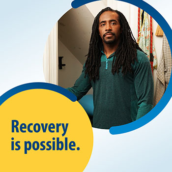 A Veteran standing indoors next to a ladder with text that says “Recovery is possible.”