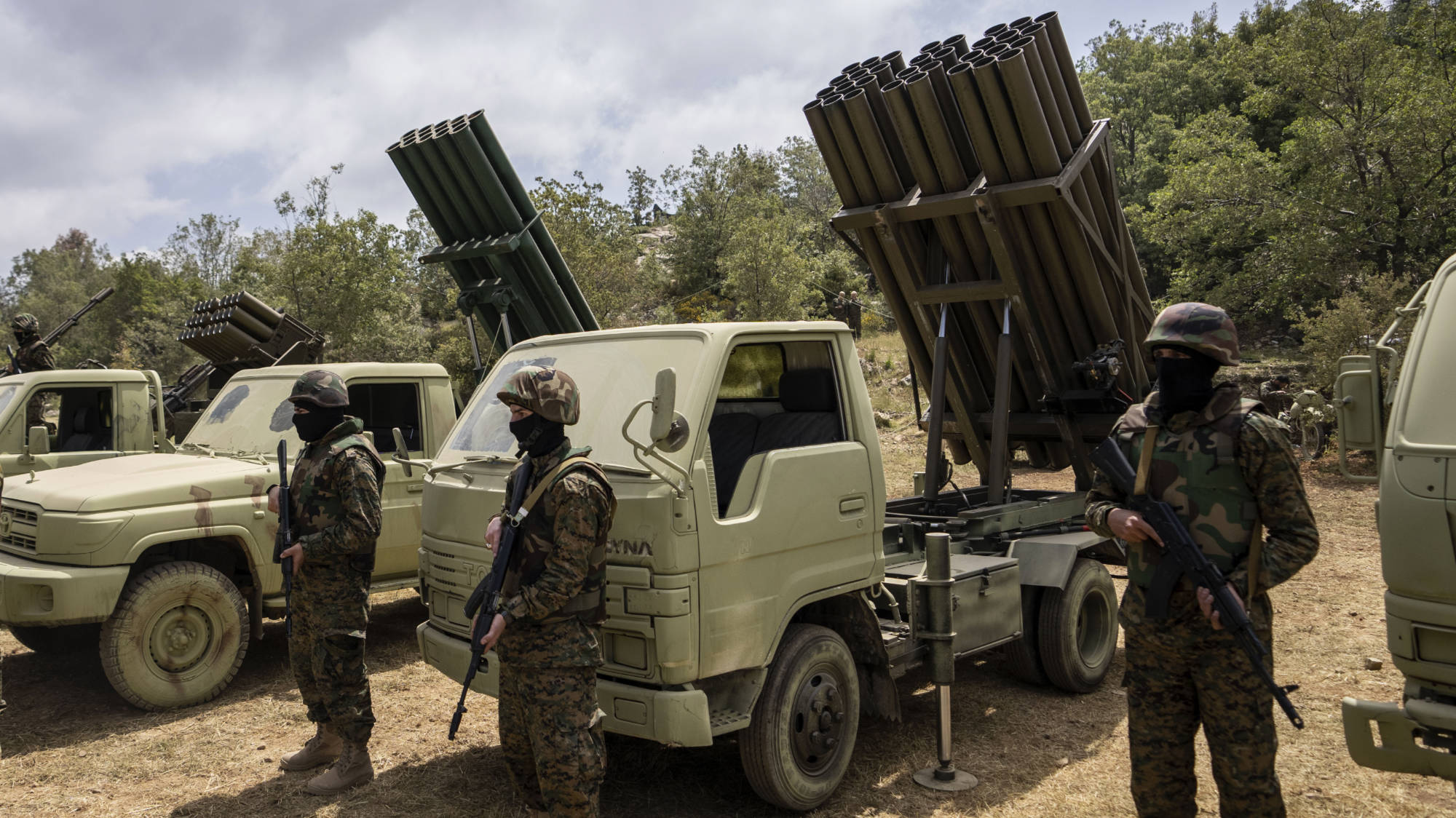 Hezbollah fighters stand in front of multiple-barrel rocket launchers (AP)