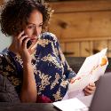 Woman with a mortgage bill in hand, talking to a counselor on the phone.