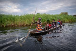 Una mujer rema con su familia en canoa por el río Zeraf, en el Viejo Fangak.