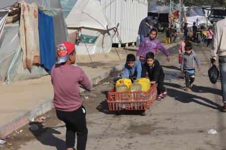 Niños palestinos desplazados llenan sus botellas de agua potable en el barrio de Al-Shaboura, en el sur de Gaza.