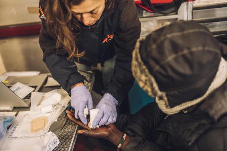 Una de nuestras enfermeras cura la mano de un joven migrante sudanés en Calais. 