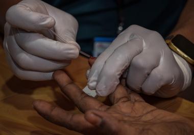 Un membre de l’équipe MSF prélève un échantillon de sang sur un patient pour effectuer un test diagnostic rapide (TDR) de l'hépatite C dans la salle de consultation de l'hôpital MSF, à Cox's Bazar, Bangladesh.