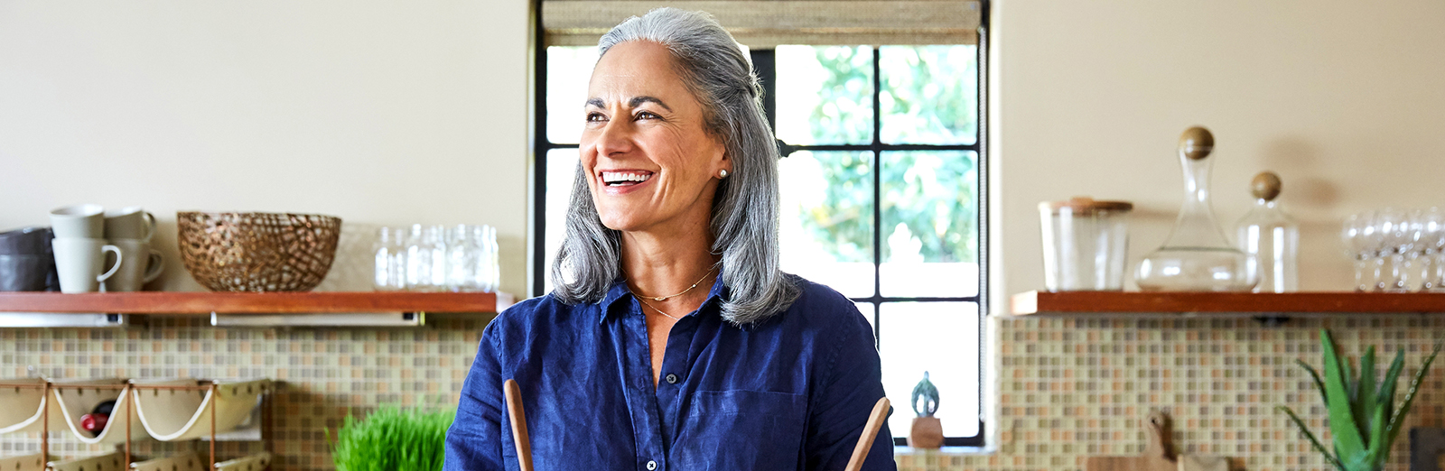 Portrait Of Mature Woman Preparing A Healthy Salad In The Kitchen At Home Laughing